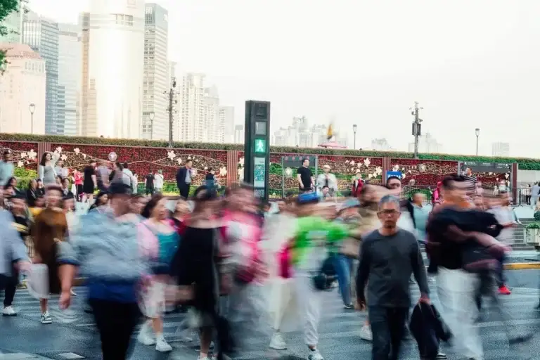 Blurred crowd of people walking across a busy city street