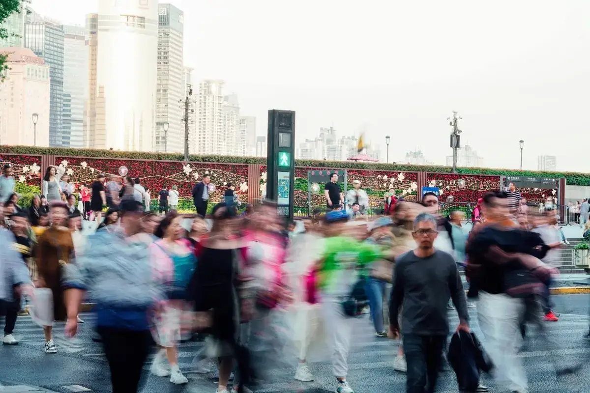 Blurred crowd of people walking across a busy city street